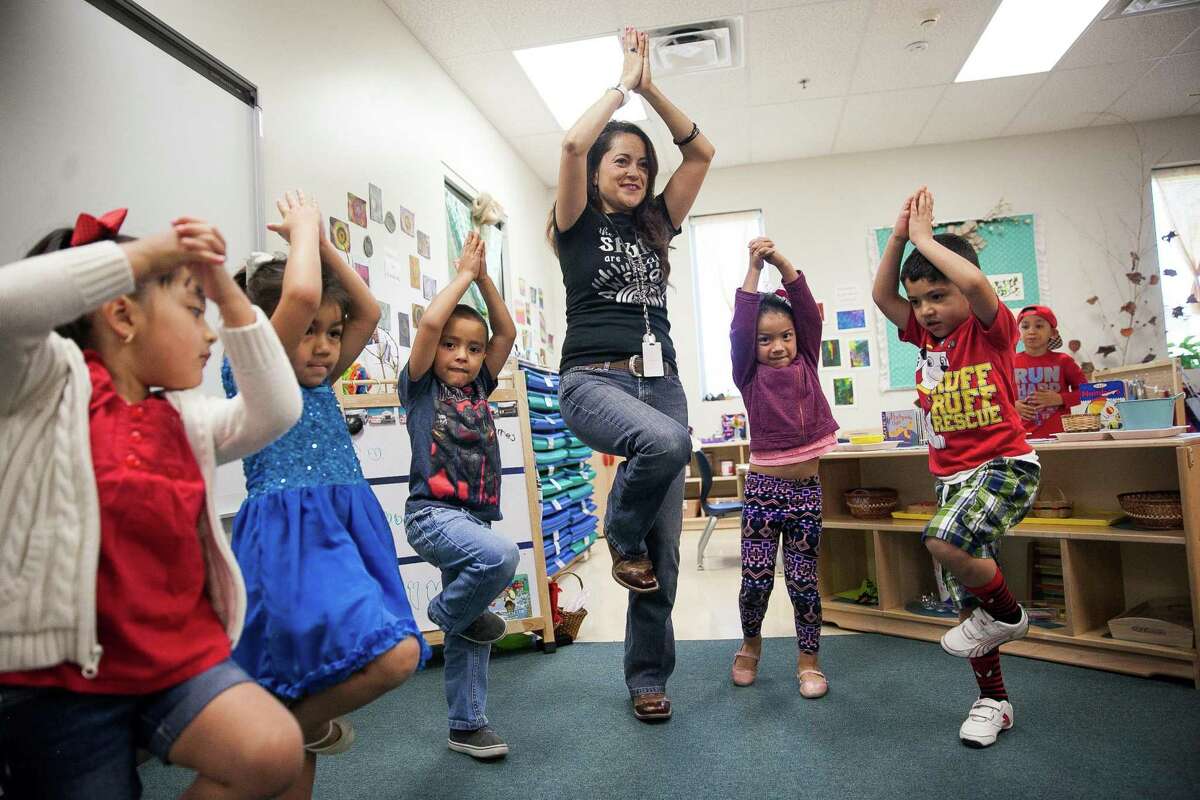 FILE - Master Teacher Marielos Romero's leads her bilingual class in a stretch that helps promote stronger balance during the movement session where the children have time to dance and move before starting their day Friday May 6, 2016 during at the Pre-K 4 SA South Education Center. Bilingual education is a data-documented success, but opposition persists, rooted in the myth that Hispanics don’t want to assimilate.