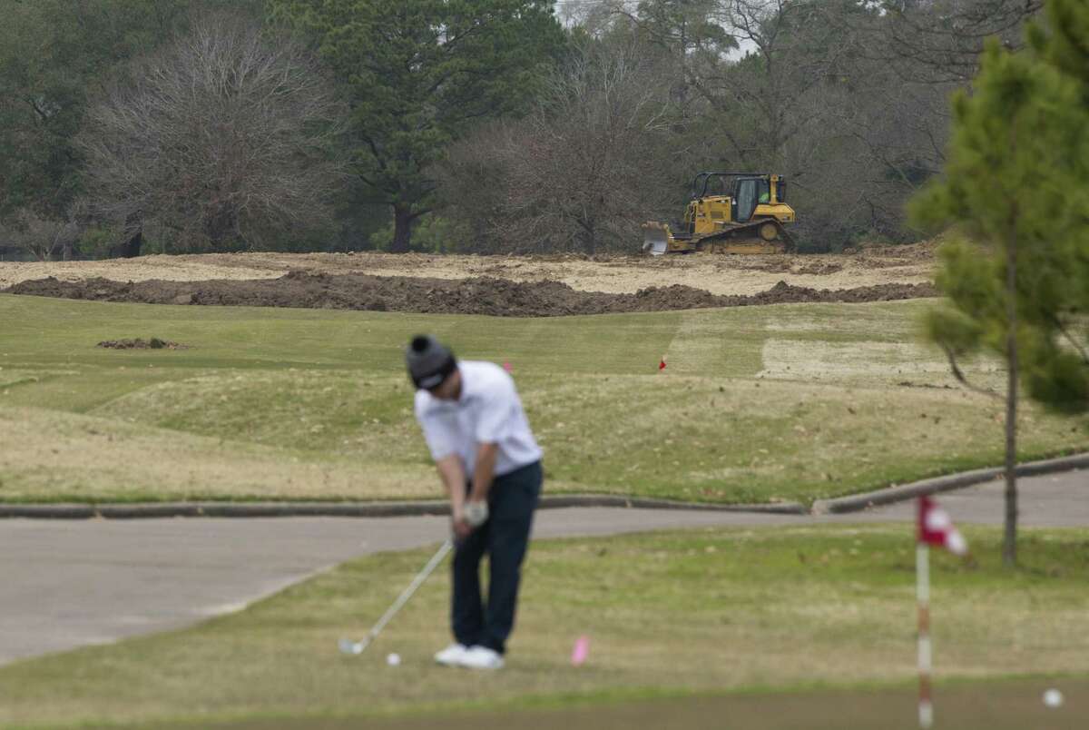 A golfer concentrates on his chipping game despite bulldozing efforts in the background helping to renovate Memorial Park Golf Course in preparation for the 2020 Houston Open.