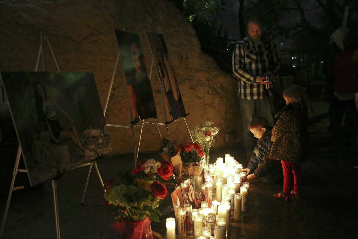 Andy Cerwin and his children, Landon, 8, and Madison, 4, pay their respects during a vigil for the Olsen family at the Grotto Sanctuary at Oblate Missions.