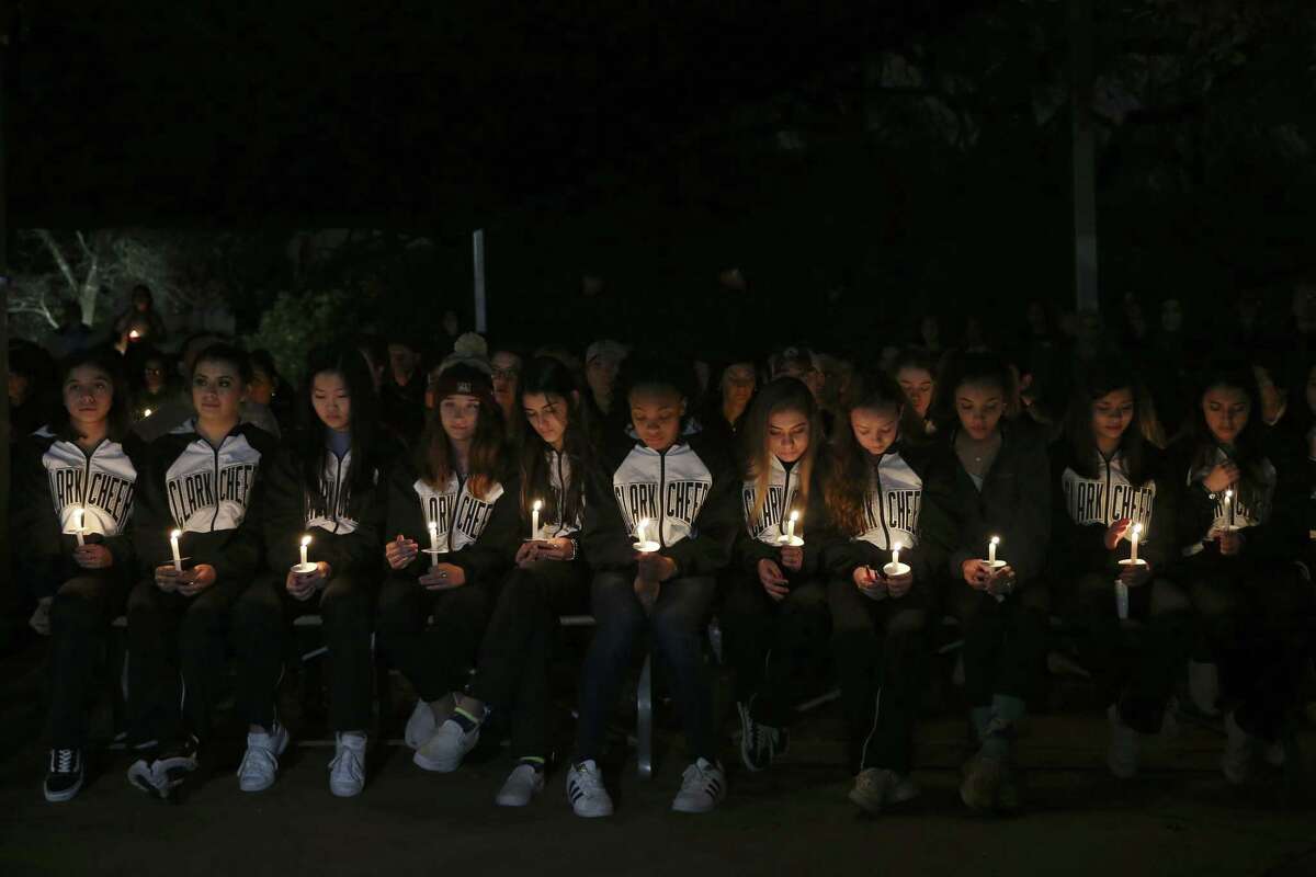 Members of the Clark High School cheerleaders squad hold candles during the vigil.