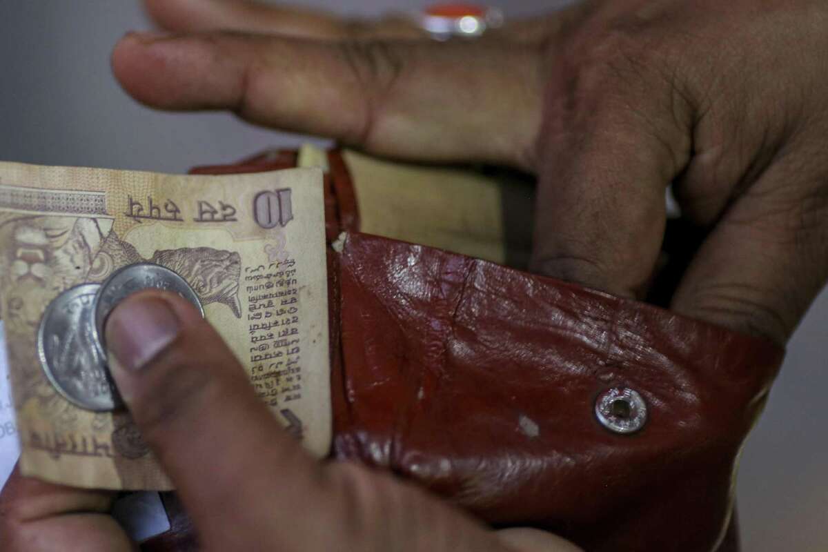 A man takes an 10-rupee banknote and one-rupee coins from a wallet on June 28, 2018, in Mumbai.