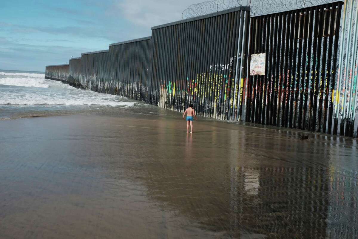 A child plays in the water by a border fence that stands along a beach this week in Tijuana, Mexico.