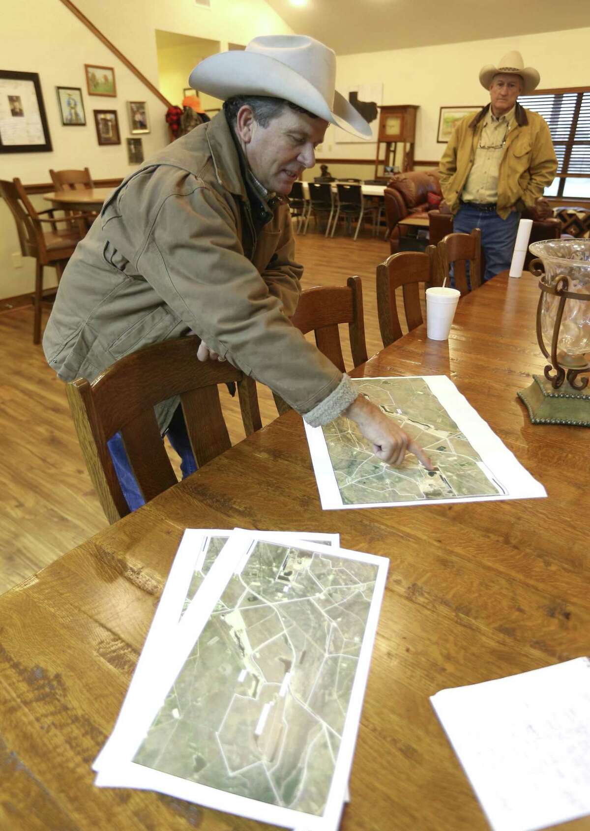Jason Peeler points to maps of his family's ranch Wednesday, Jan. 16, 2018, as he tells visitors to the ranch about damage he says has been caused to parts of the property by San Miguel Electric Cooperative's coal-burning power plant.