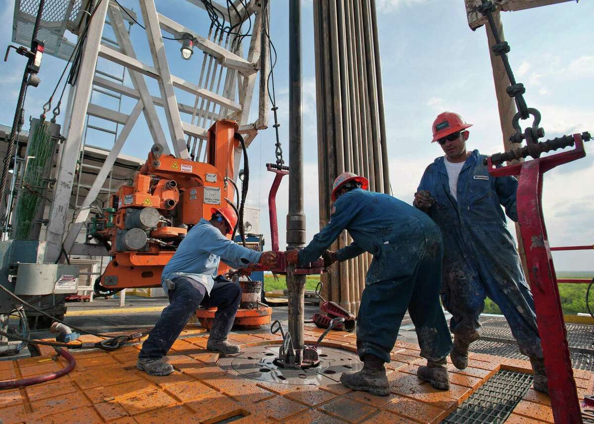 Floor hands Jose Garza, left, Jose Salinas, center, and Omar Cano make a pipe connection on Orion Drilling Co.'s Perseus drilling rig near Encinal in Webb County, Texas.
