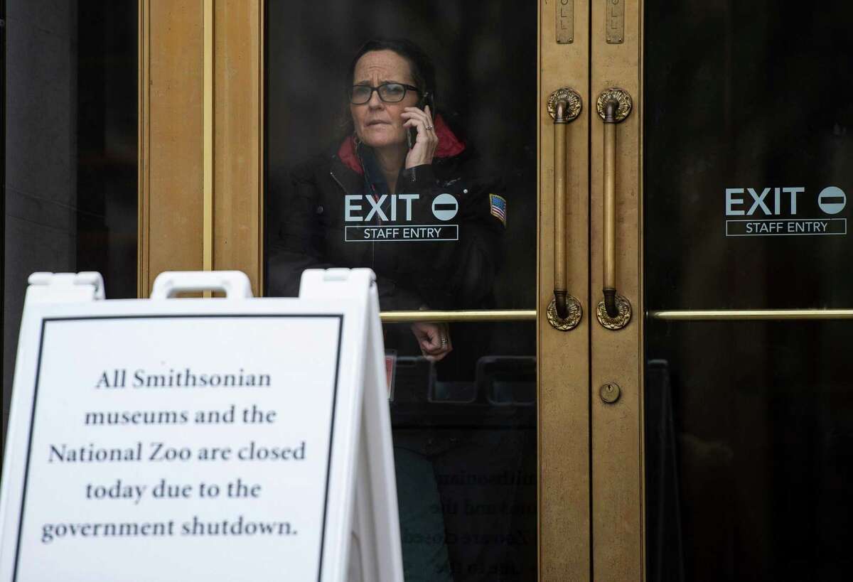 A U.S. government employee talks on the phone as she looks out of one of the closed Smithsonian museums in Washington.