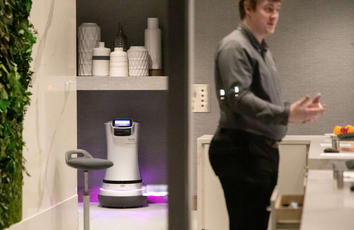 Rose the robot recharges near the front desk with Devin Leclere at The Hotel Trio