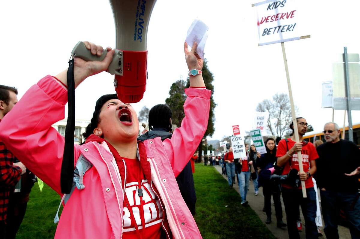 Skyline High School teacher Donna Salonga yells into a bullhorn to motivate teachers on a picket line in front of Oakland Technical High School before a march to school district offices in a one day walkout to warn administrators of a possible strike if their contract demands aren't met in Oakland, Calif. on Friday, Jan. 18, 2019.