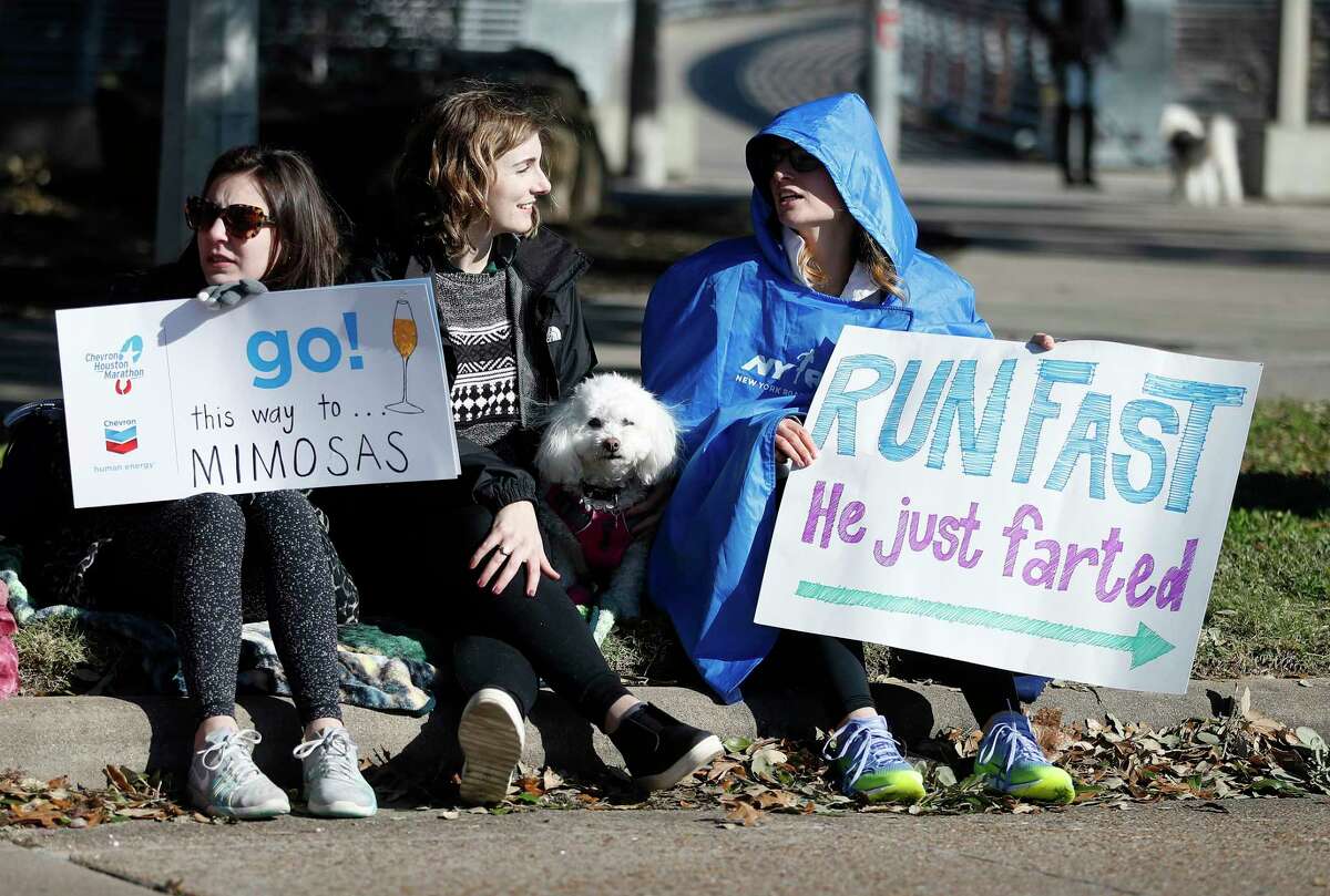 Half-marathon supporters hold signs to cheer on runners at mile marker 11 at Montrose and Allen Parkway during the Chevron Houston Marathon, Sunday, Jan. 20, 2019, in Houston.