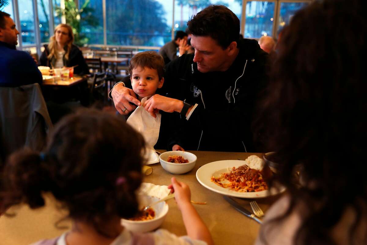 Coast Guard's James Weigand puts a napkin on his son, Parker, 2, as his wife, Krysia and daughter, Sienna, 4, take part as South Beach Yacht Club provides a spaghetti dinner for members of the Coast Guard at Pier 40 in San Francisco, Calif., on Sunday, January 20, 2019.