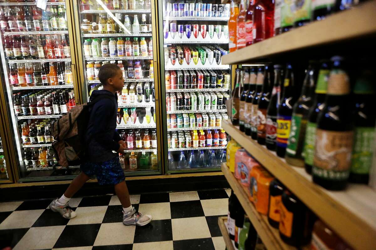 Zaire Lowrey, 12, walks past the sodas sitting in the fridges at Ashby Supermarket on Friday, April 14, 2017, in Berkeley, Calif.