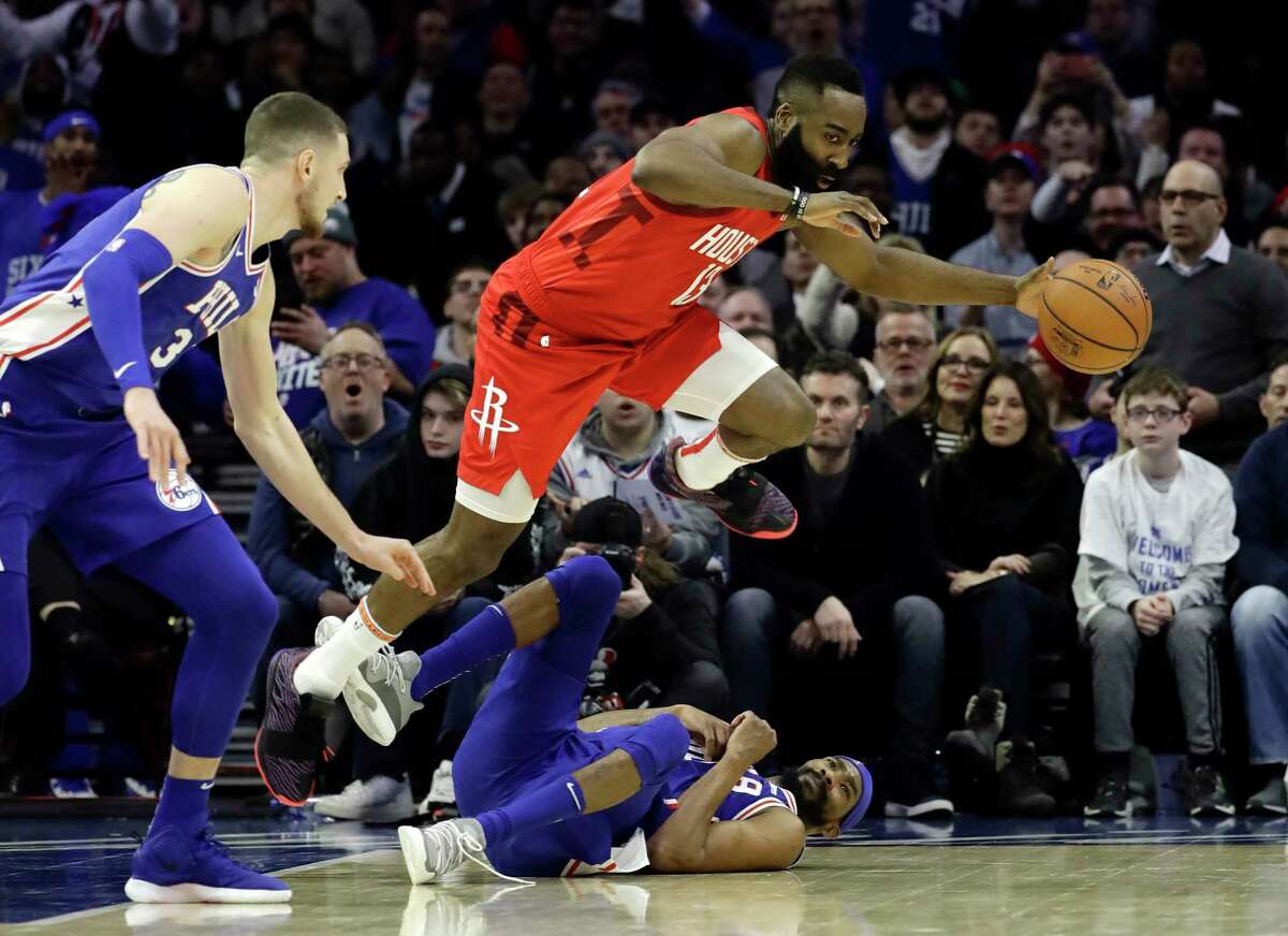 Houston Rockets' James Harden, top, leaps over Philadelphia 76ers' Corey Brewer as Mike Muscala looks on during the first half of an NBA basketball game, Monday, Jan. 21, 2019, in Philadelphia. (AP Photo/Matt Slocum)