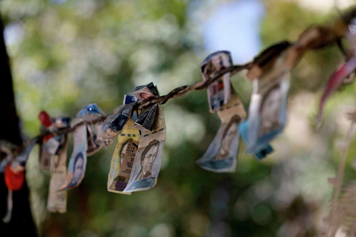 Discontinued Venezuelan bank notes hang above a cigarette stand in the San Jose del Avila neighborhood in Caracas, Venezuela, Tuesday, Jan. 22, 2019. Working class neighborhoods in Venezuela's capital sifted through charred rubble and smoldering trash on Tuesday, following a day of isolated protests in response to the arrest of National Guardsmen who mounted an uprising against President Nicolas Maduro.