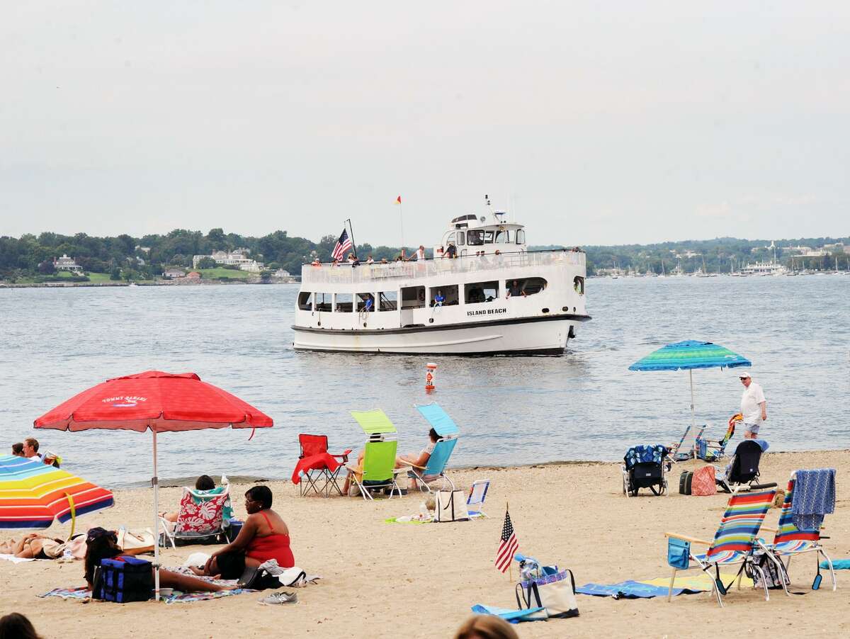 As people enjoy the beach, the Island Beach ferry nears the dock at Island Beach off the coast of Greenwich, Conn., Saturday, August 25, 2018, on the day a ceremony was held commemorating the 100th anniversary of when the island, that is used as a public beach, was donated to the Town of Greenwich in 1918.