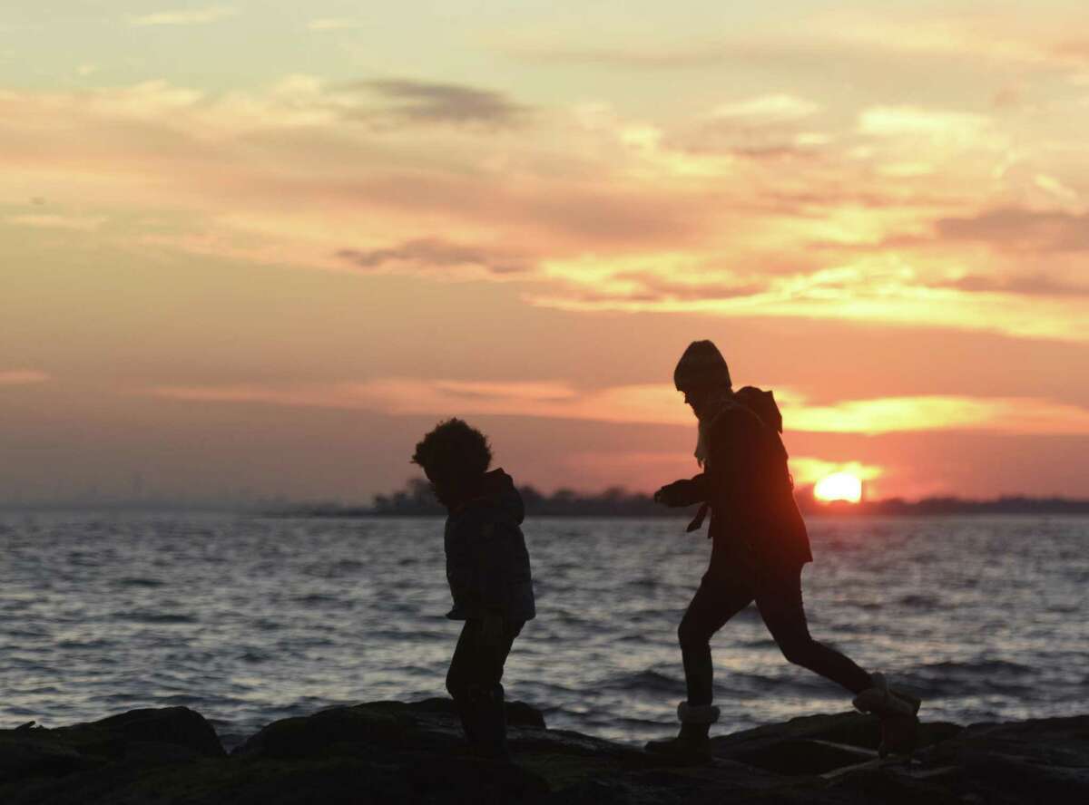 Greenwich's Christine Rathbun and her son, Isaiah Smith, 5, traverse rocks overlooking the sunset at Greenwich Point Park in Old Greenwich, Conn. Tuesday, Dec. 19, 2017.