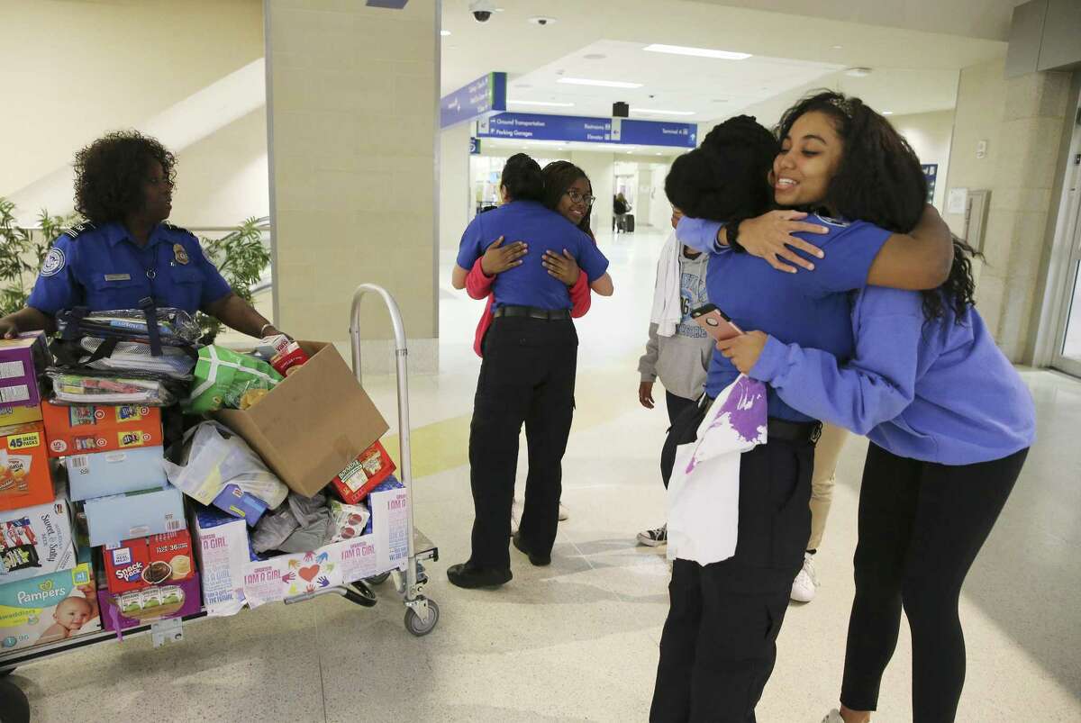 Reanna Wilson (right) of the local chapter of Girl Up gets a hug from TSA Lead Officer Chynae Raiford after the nonprofit group that empowers young women donated food and other items to help children of TSA government workers at the San Antonio International Airport on Wednesday, Jan. 23, 2019.