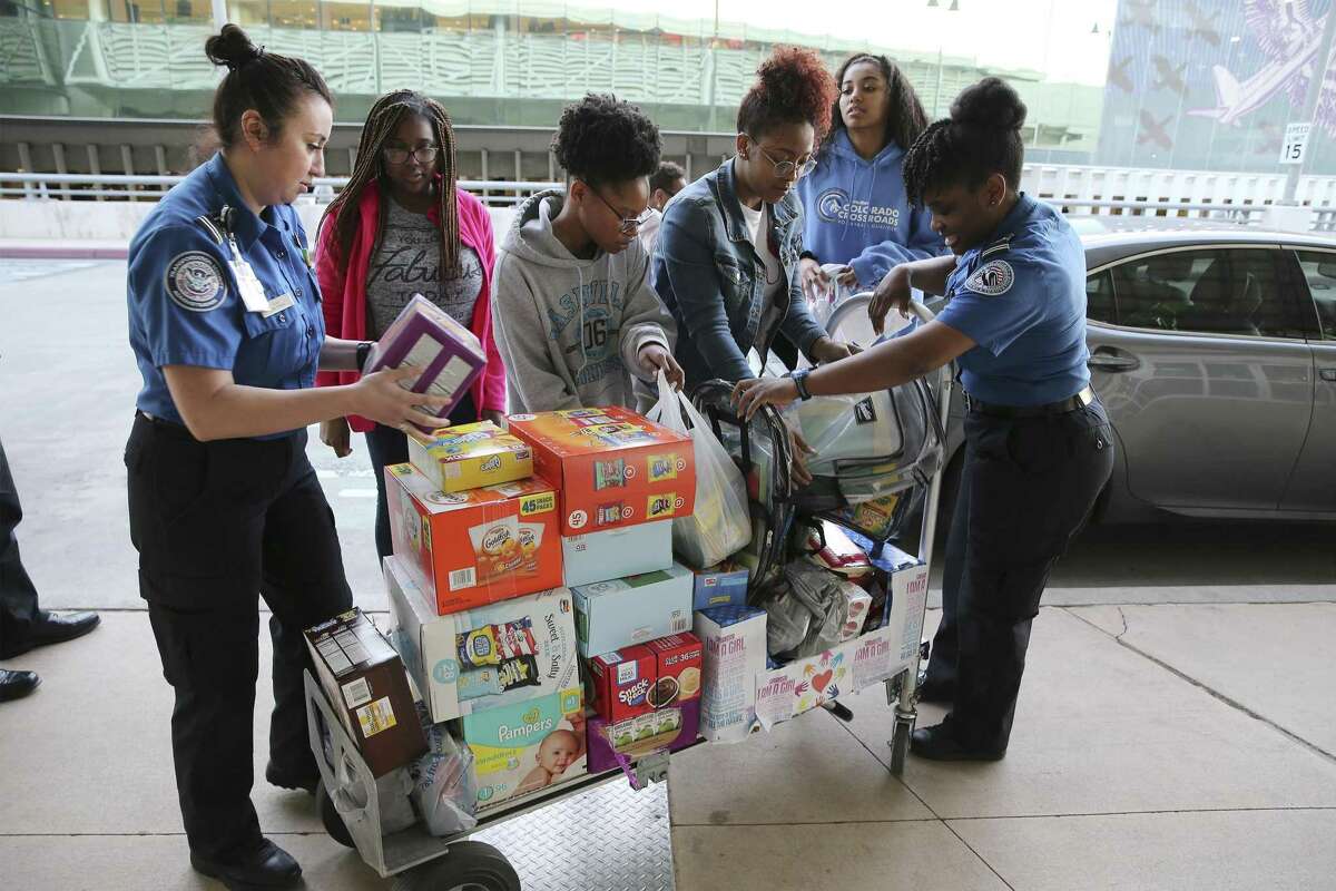 TSA Lead Officers Tiffany Rios (left) and Chynae Raiford (right) help load a cart with donated items from Brittney Carson (second from left), Simone Green, Jada Young and Reanna Wilson - all members of the local chapter of Girl Up, a nonprofit that empowers young women on Wednesday, Jan. 23, 2019. The donated food items and other supplies went to help children of TSA government workers at the San Antonio International Airport. The four young women from the local chapter along with two parent chaperones off-loaded a truckload of items received by two TSA officers. With the government shutdown going on for more than a month, local TSA personnel were grateful for the donations which helps them and their families during the shutdown. (Kin Man Hui/San Antonio Express-News)