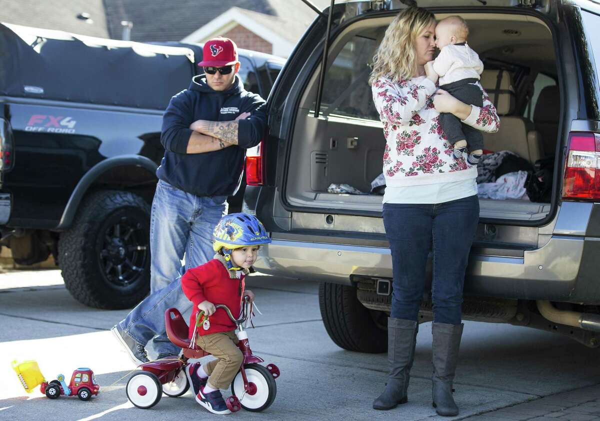 Coast Guard MK2 Terence Totten, left, watches his son, Braxton, ride his tricycle, as his wife, Ashley holds their infant son, Maddox, on Sunday, Jan. 13, 2019, in League City. The Tottens will miss their first paycheck Tuesday due to the longest government shutdown ever. The shutdown affects the Coast Guard, which is part of the Department of Homeland Security, one of the agencies affected by the impasse over President Trump's demand for $5.7 gillion to extend the border wall.
