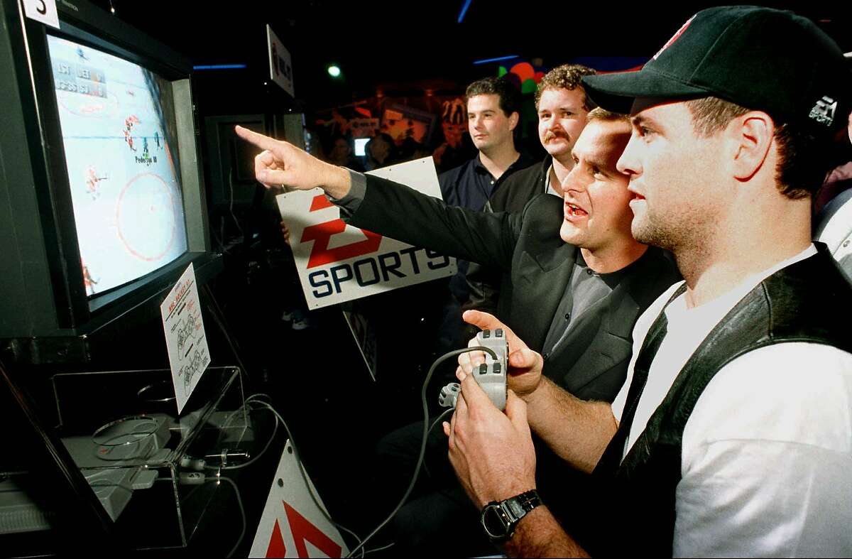 Actor Dave Coulier, second left, assists San Jose Sharks All-Star center Owen Nolan, right, play a hockey video game during the National Hockey League 97 video game tournament Thursday, Jan. 16, 1997, in San Jose, Calif. The video tournament is part of the festivities surrounding the upcoming NHL ALL-STAR games that start Friday night.