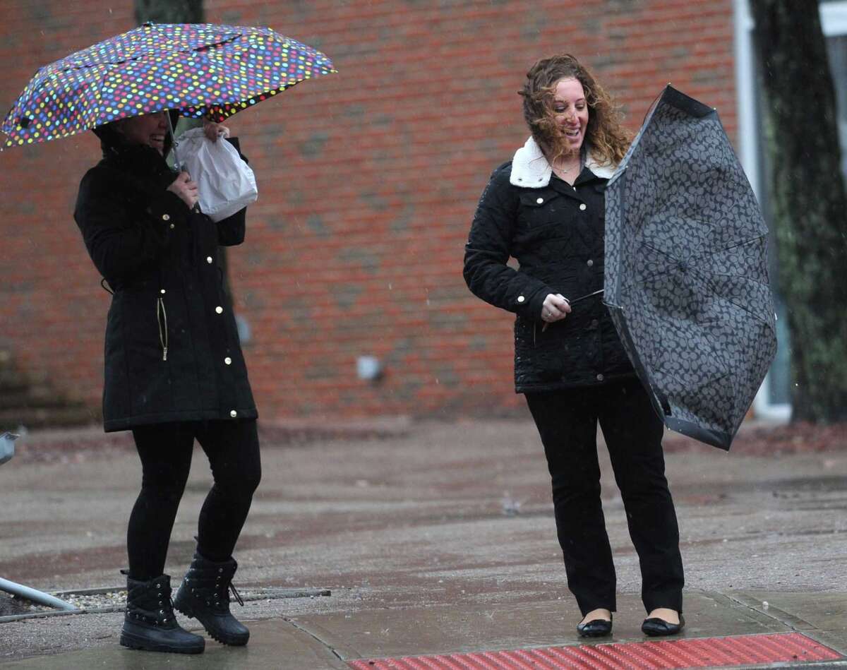 Residence Inn employees Dawn Gasper and Michelle Gordon try to keep their umbrellas from blowing out during the rainstorm Thursday, January 24, 2018, in Norwalk, Conn.