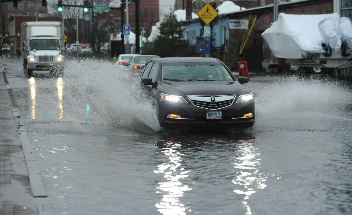 Motor vehicles drive through a flooded Water Street during the rainstorm Thursday, January 24, 2018, in Norwalk, Conn. The Department of Public Works is working to select a consultant for a city wide drainage study.