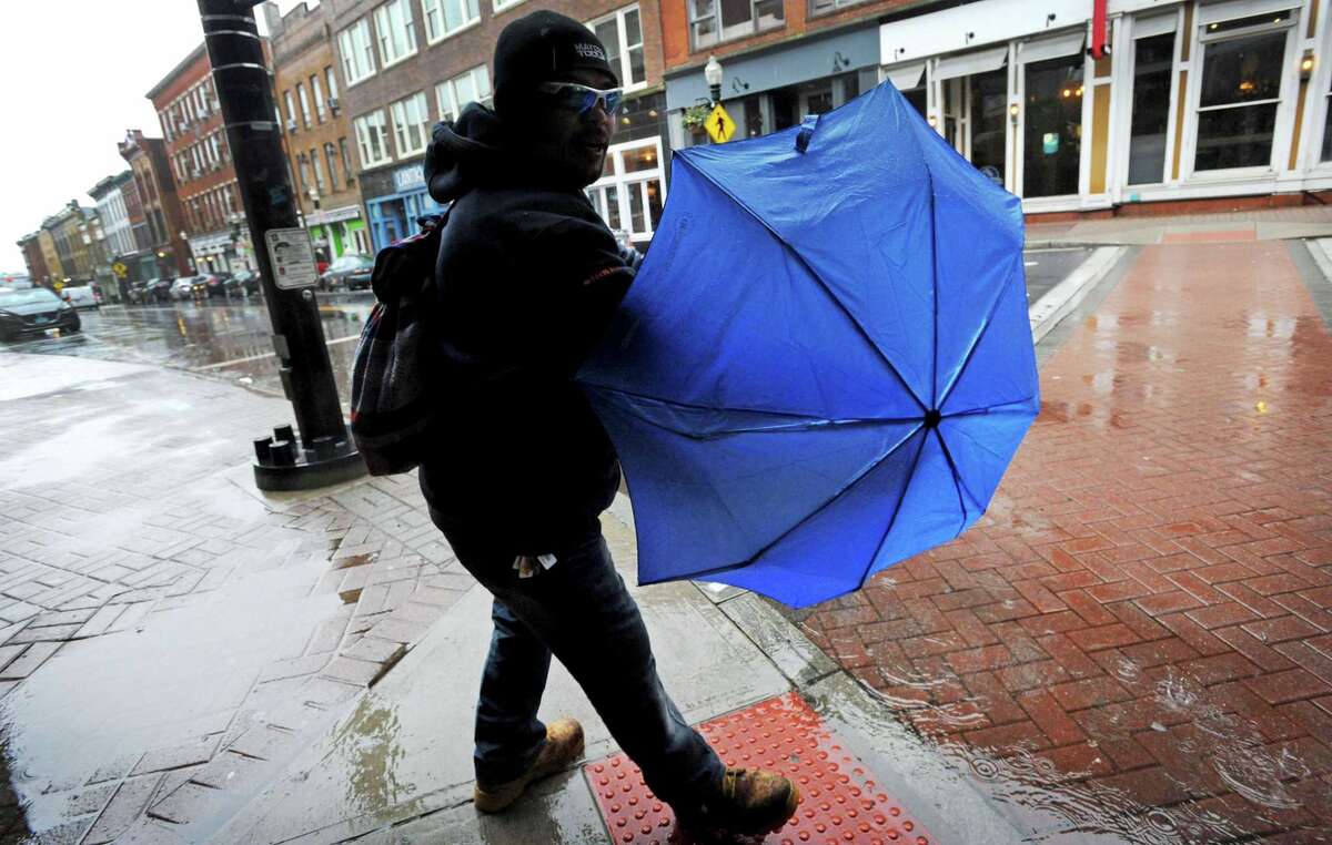 Ricardo Lopez tries to keep his umbrella open while walking along Washington Street during the rainstorm Thursday, January 24, 2018, in Norwalk, Conn.