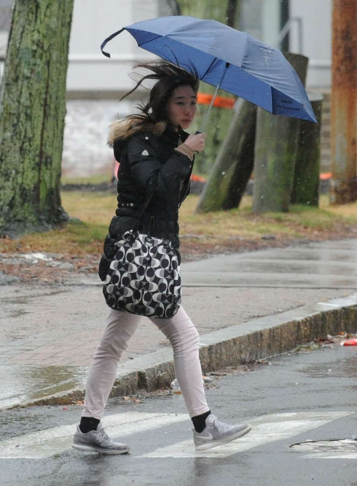 A pedestrian crosses Washington Street during the rainstorm Thursday, January 24, 2018, in Norwalk, Conn.