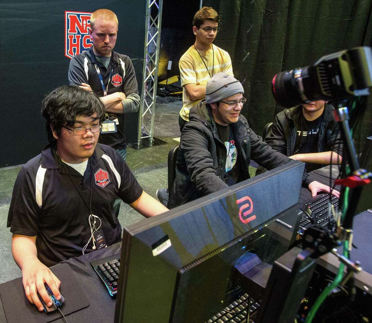 Manchester High School eSports coach Sam Warner, back left, watches over team members Justin Lumaque, left front, and Bryan Santaban during the CIAC eSports championship.