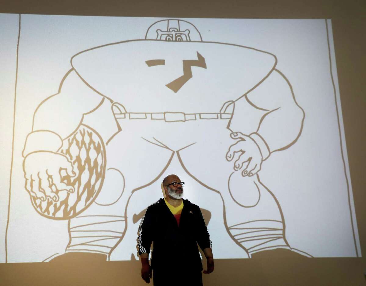 Artist Trenton Doyle Hancock stands in front of one of his enlarged panels projected onto the wall of the Menil Collection, Friday, Jan. 18, 2019, in Houston, creating a special installation that opens Jan. 25 as part of the museum's "Contemporary Focus" program. The gallery includes a room that holds a series of drawings recently purchased by the Menil about one of the characters from Hancock's ongoing comics-inspired epic: His alter-ego character Torpedo Boy is lured into a dark room to turn on a light; and when it comes on, he is surrounded by figures in Ku Klux Klan robes.