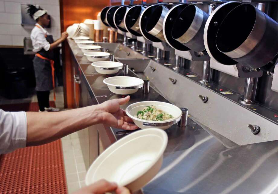 A worker lifts a lunch bowl off the production line at Spyce, a restaurant which uses a robotic cooking process, in Boston. Robots aren’t replacing everyone, but a quarter of U.S. jobs will be severely disrupted as artificial intelligence accelerates the automation of today’s work, according to a Brookings Institution report. Photo: Charles Krupa, STF / Associated Press / Copyright 2019 The Associated Press. All rights reserved.