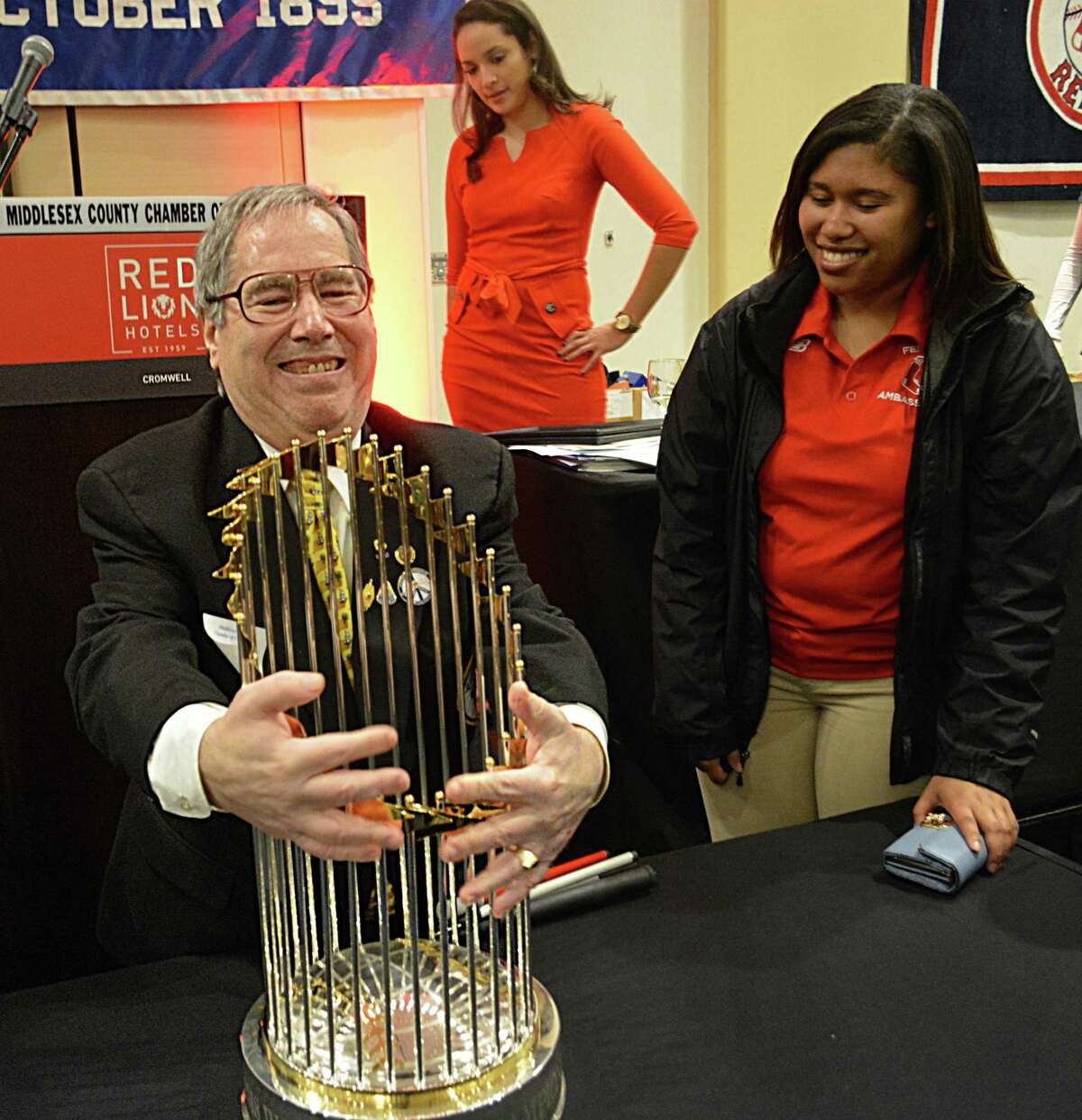 Longtime Middletown Lions Club member Marty Knight was honored at the chamber’s member breakfast Friday in Cromwell. Knight, shown here touching the Boston Red Sox World Series trophy (something no others were allowed to do) advocates for the blind in Middletown and statewide.