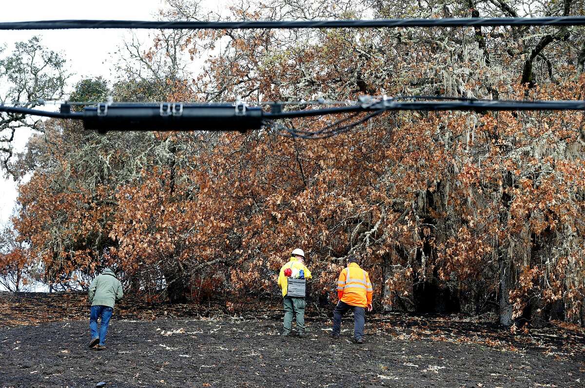 An inspection team walks on the charred property below power lines on Bennett Lane in Calistoga, Calif. on Friday, Nov. 10, 2017 where authorities believe the Tubbs Fire originated. PG&E filed legal papers suggesting that third party electrical equipment, not theirs, may have been the cause of last month's deadly Tubbs Fire.