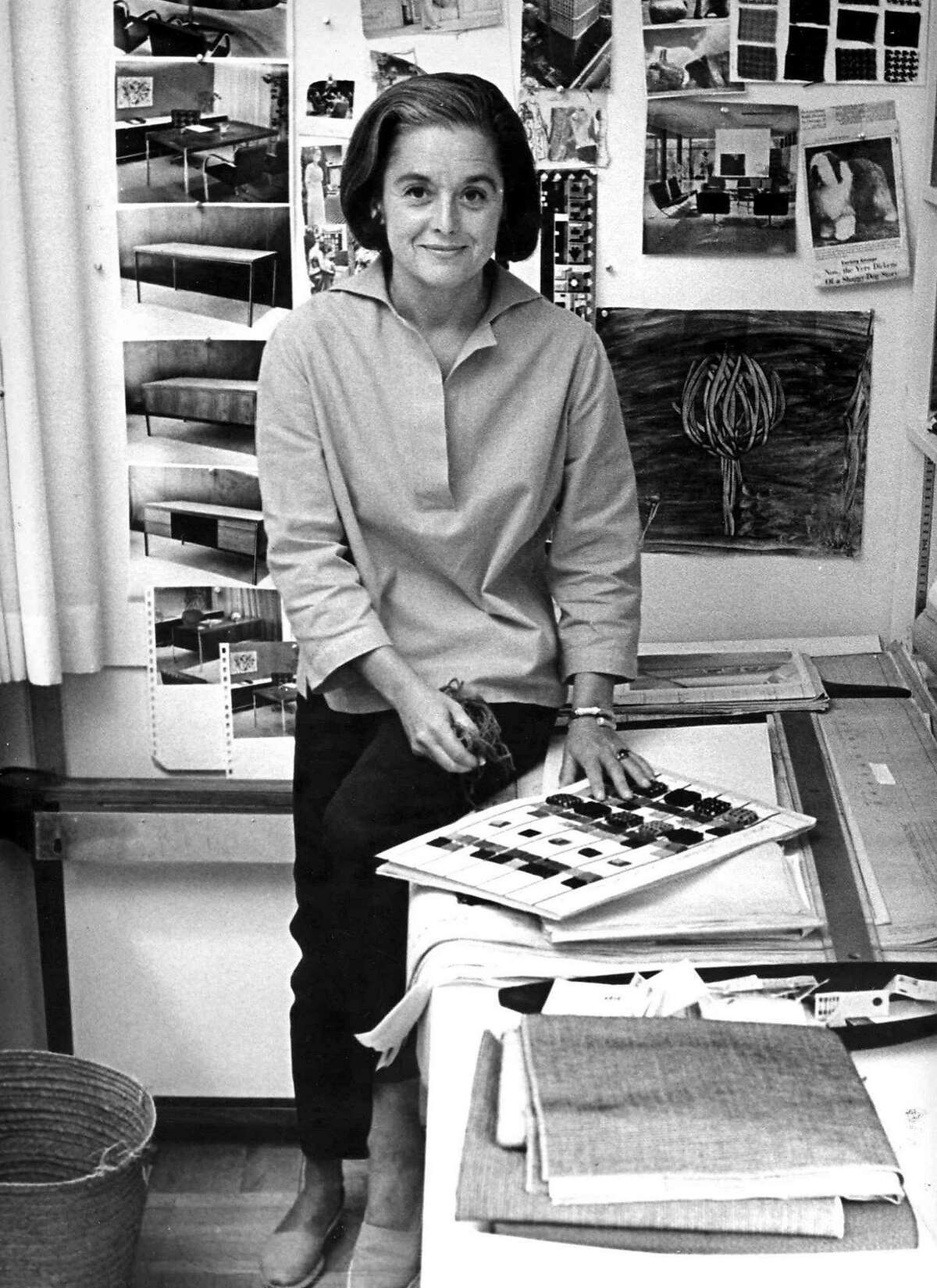 Portrait of American architect and furniture designer Florence Knoll Bassett as she sits on the edge of a table with a book of fabric swatches in front of her, 1961. (Photo by Ray Fisher/The LIFE Images Collection/Getty Images)
