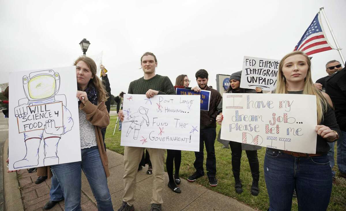 Kirsi Kuutti of Duluth, MN, left, Desmond O'Connor of Dickinson, center, and Sandra Jones, right, who was about to start a NASA job, protest with others outside of NASA's Johnson Space Center against the government shutdown Tuesday, Jan. 15, 2019, in Houston.