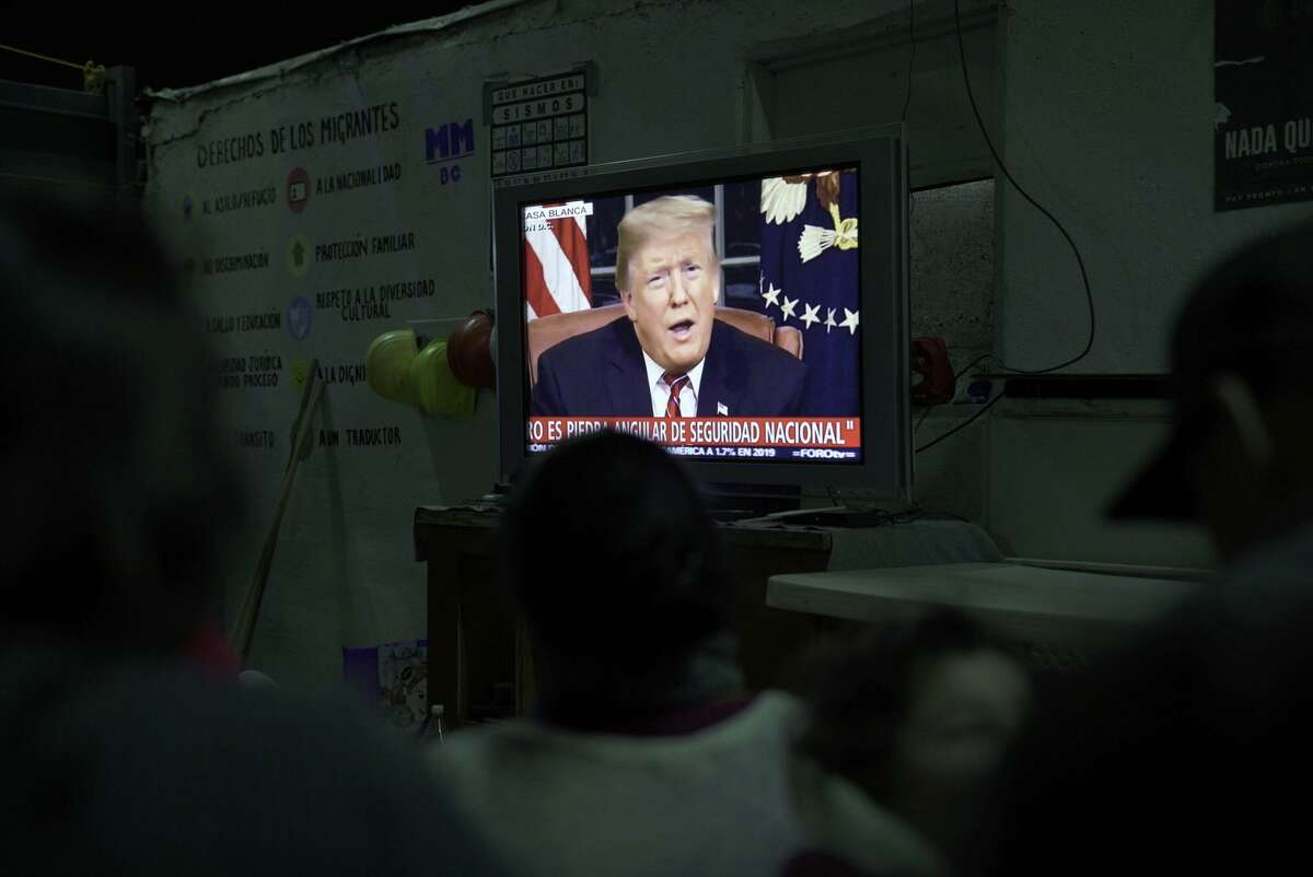 Migrants on Tuesday night, Jan. 9, 2018, at a shelter in Tijuana, Mexico, watching President Donald Trump’s address. The president's latest call for a border wall stirred weariness among leaders and citizens alike. (Kitra Cahana/The New York Times)