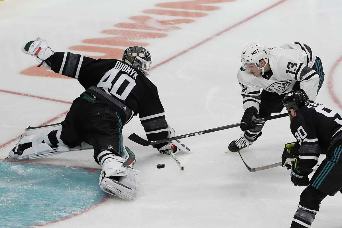 Central Division's Devan Dubnyk, left, of the Minnesota Wild, defends against Metropolitan Division's Mathew Barzal (13), of the New York Islanders, during the first half of the NHL hockey All-Star Game final in San Jose, Calif., Saturday, Jan. 26, 2019. (AP Photo/Jeff Chiu)