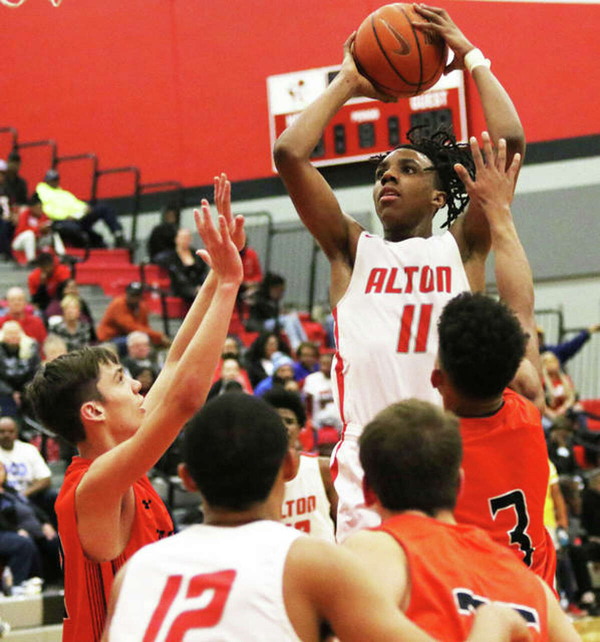 Alton’s Donovan Clay (11) rises up in the lane for a shot over Edwardsville defenders during the Redbirds’ Southwestern Conference victory on Tuesday at Alton High in Godfrey. The Redbirds were in Galesburg on Saturday and Clay scored 23 points in a shootout win over Rock Island.