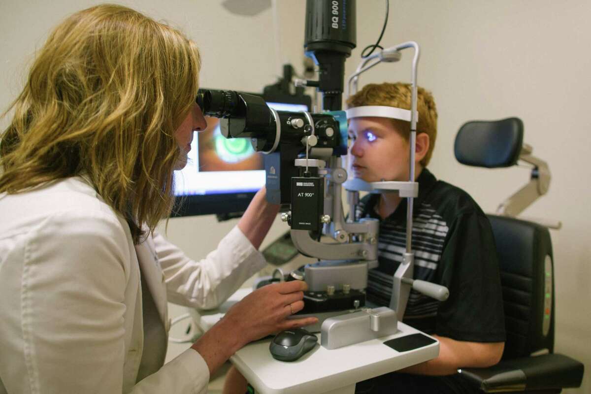 Kathryn Richdale, UH associate professor and optometrist at the University Eye Institute examines 12-year old Joaquin Martinez, a patient of the University’s Myopia Management Service.