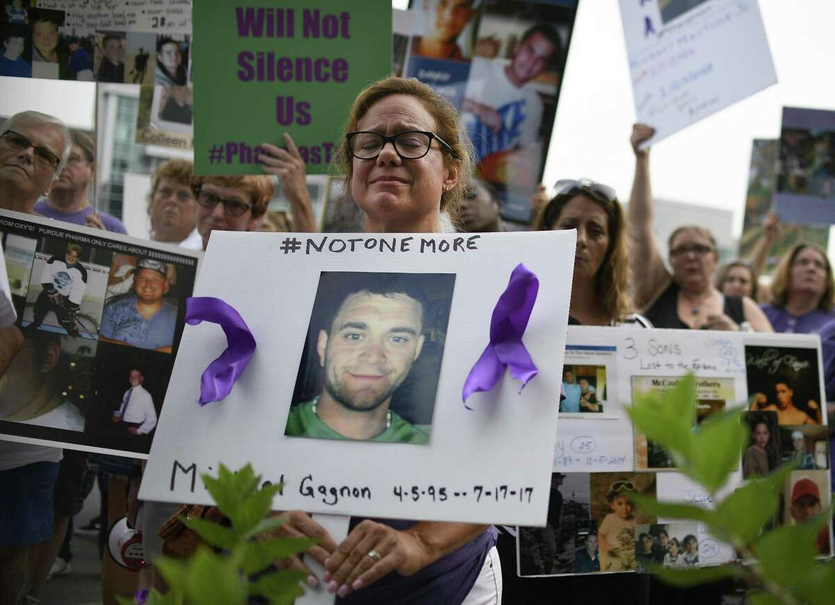 Christine Gagnon, of Southington, Conn., holds a sign during a protest with others who have lost loved ones to OxyContin and Opioid overdoses at the Purdue Pharma headquarters in Stamford, Conn., on Friday, Aug. 17, 2018. Gagnon lost her son Michael 13 months earlier. (AP Photo/Jessica Hill)