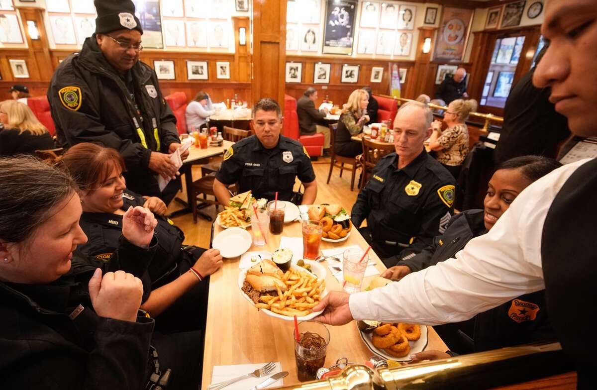Houston Police Officer E. Johnson, of the Southeast Command Station, standing left, visits with fellow officers from the Midwest Division Officer G. Durrill, left, Officer M. Lugo, Sr. Officer A. Pena, center, Sgt. D. Hopper, and Lt. K.L. Carey, right as they are served lunch by Jesus Guzman at Kenny & Ziggy’s New York Delicatessen, 2327 Post Oak, as he waits to be seated Tuesday, Jan. 29, 2019 in Houston. In the wake of the shooting of five police officers in southeast Houston on Monday, the restaurant offered free meals on Tuesday in appreciation to all the officers of the Houston Police Department.