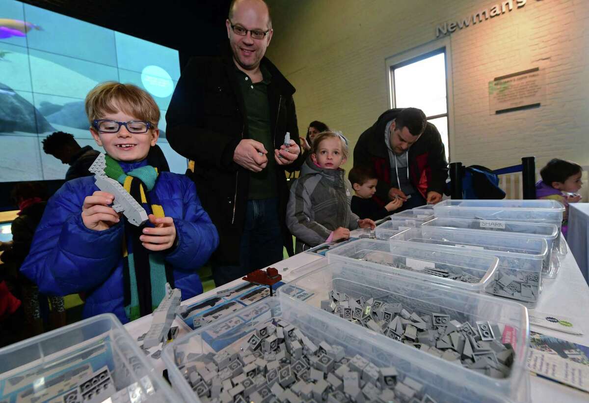 Visitors to The Maritime Aquarium including Oscar Egmond, 7, and his dad Lennart Egmond of Weston help Play-Well TEKnologies engineers create an enormous aquarium-themed scene using Lego building blocks during