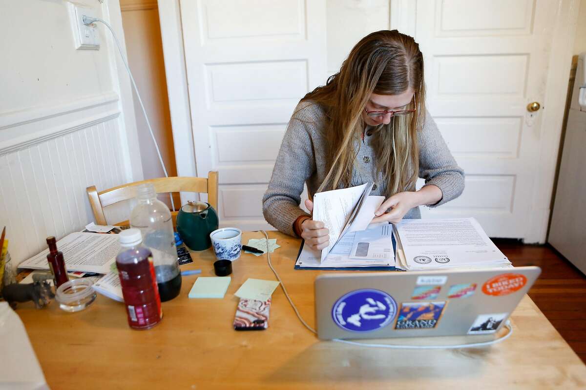Katie Waddle, an SFSU student trying to get insurance through Covered California, looks through the large folder of paperwork she has collected while trying to get insurance in her home on Monday, January 21, 2019 in San Francisco, Calif.