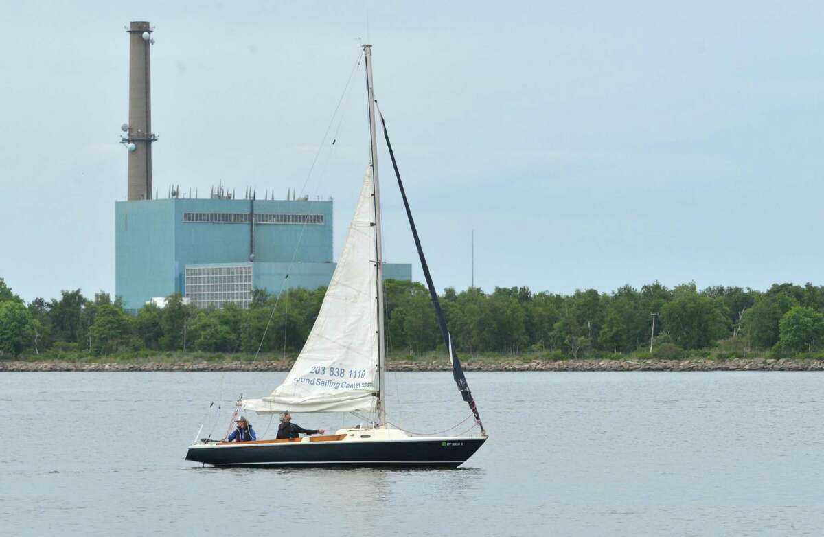 A sailboat heads into Norwalk Harbor with Manresa Island and the decommissioned power plant in the background in June 2018 in Norwalk Conn.