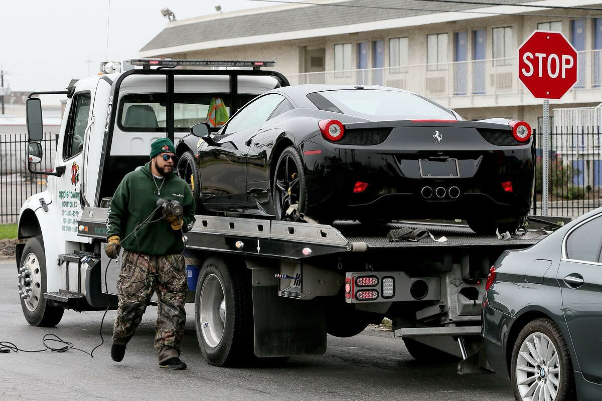 J.C. Cole with Apple Towing walks beside a 2013 Ferrari 458 Italia Coupe, one of a reportedly 50 to 60 cars seized by agents from the I.R.S and D.E.A. and officers from the Bexar County Sheriff's office at MGM Auto, 5711 Industry Park, on Thursday, Jan.31, 2019. Two people, including Karen Mgerian, were initially arrested on money laundering charges. The Ferrari was listed on MGM Auto's website for $227,000.
