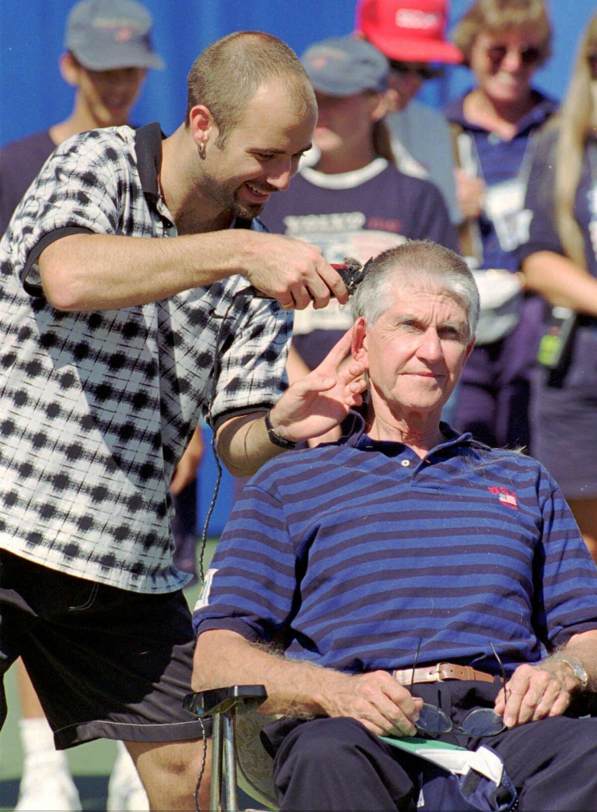 Andre Agassi, left, shaves Volvo International Tennis Tournament Director Jim Westhall's head after Agassi won the Volvo International singles title in New Haven, Conn., Sunday, Aug. 20, 1995, by defeating Richard Krajicek of the Netherlands 3-6, 7-6(7-2), 6-3. Agassi made a bet with Westhall that if he won the tournament Westhall, who is known for having a large head of hair, would let him shave Westhall's head. (AP Photo/John Dunn)