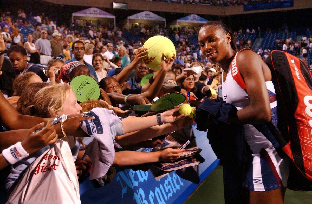 Venus Williams signs autographs after defeating Meghann Shaughnessy on Aug. 20, 2002