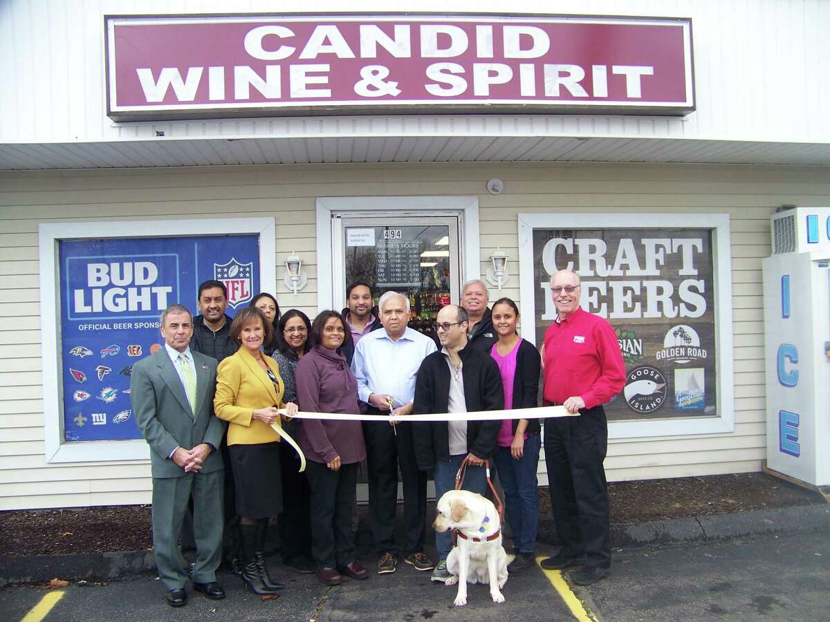 CHEERS!: Candid Wine & Spirit, 494 Washington Ave. in North Haven, recently celebrated its grand opening with a ribbon-cutting ceremony. From left are North Haven First Selectman Mike Freda; Dee Prior-Nesti, executive Director, Quinnipiac Chamber of Commerce; Bhavna Patel, owner; Navin Patel, owner; Vishal Patel with guide dog Febe; Unnati Patel, Kevin O’Rourke of Fish Window Cleaning, past board chairman of the Quinnipiac Chamber of Commerce; and (back row, center) Jay Patel. The package store offers a variety of top shelf scotch, bourbon, tequila and vodka in addition to a large wine list and craft beer. For information, call 203- 239-3562.