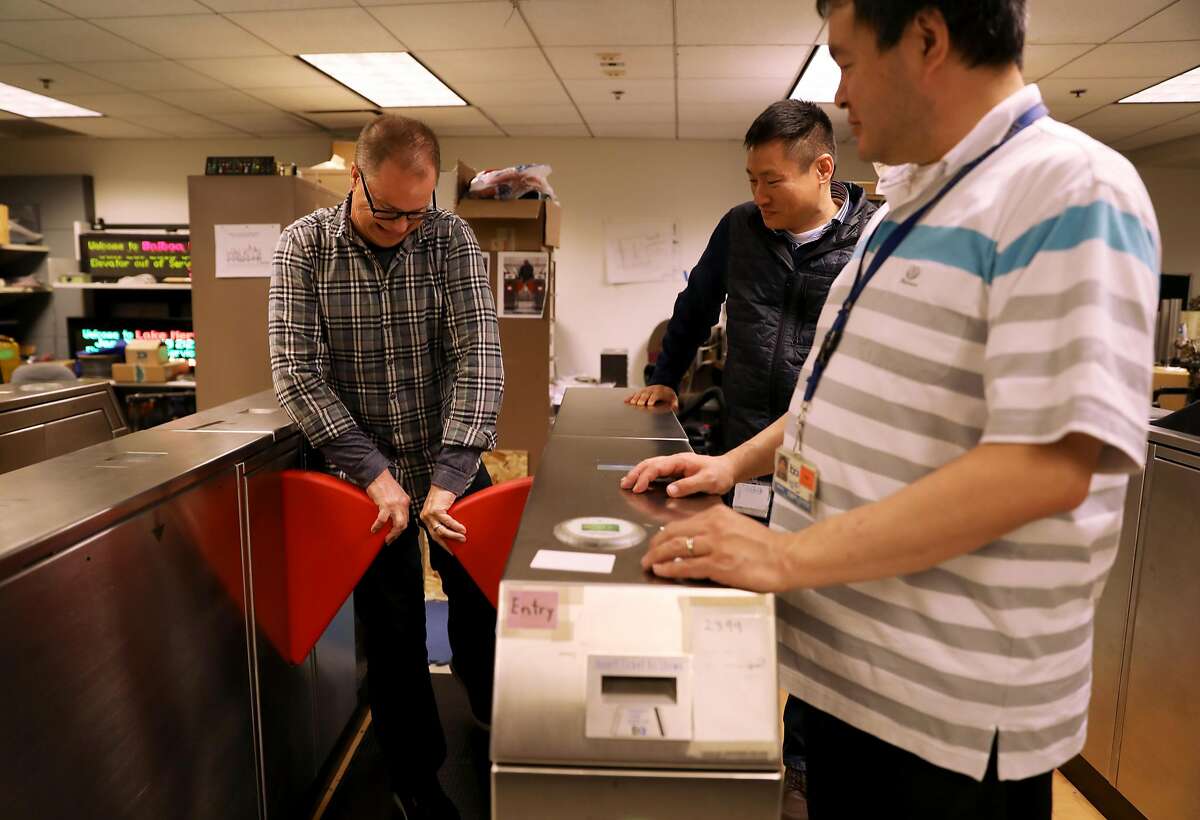 Jim Allison (left), media relations manager, tries to open a barrier as John Yen, manager for fare collection engineering, and Weldon Chen, senior computer systems engineer, look on in the Fare Collection Engineering Machinery Laboratory at BART headquarters in Oakland, Calif., on Tuesday, January 29, 2019. BART is testing new, sturdier fare gates meant to ward off fare cheaters.