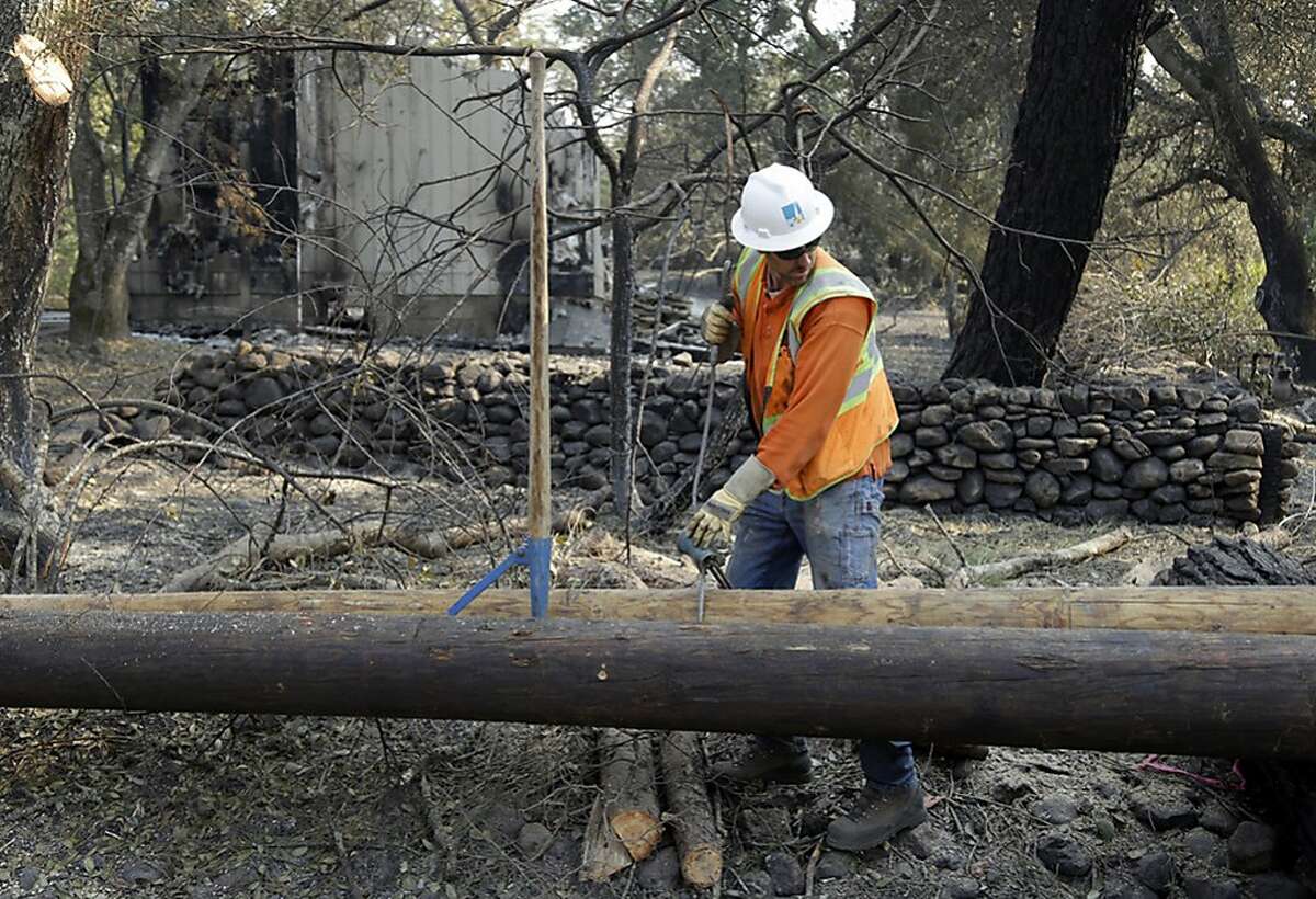 FILE - In this Oct. 18, 2017 file photo, a Pacific Gas & Electric worker replaces power poles destroyed by wildfires in Glen Ellen, Calif. U.S. prosecutors are urging a federal judge to work with a court-appointed monitor to determine ways Pacific Gas & Electric Co. can prevent its equipment from starting more wildfires. In a court filing Wednesday, Jan. 23, 2019, the U.S. attorney's office in San Francisco said Judge William Alsup should refrain from immediately imposing new requirements on the utility. (AP Photo/Ben Margot, file)