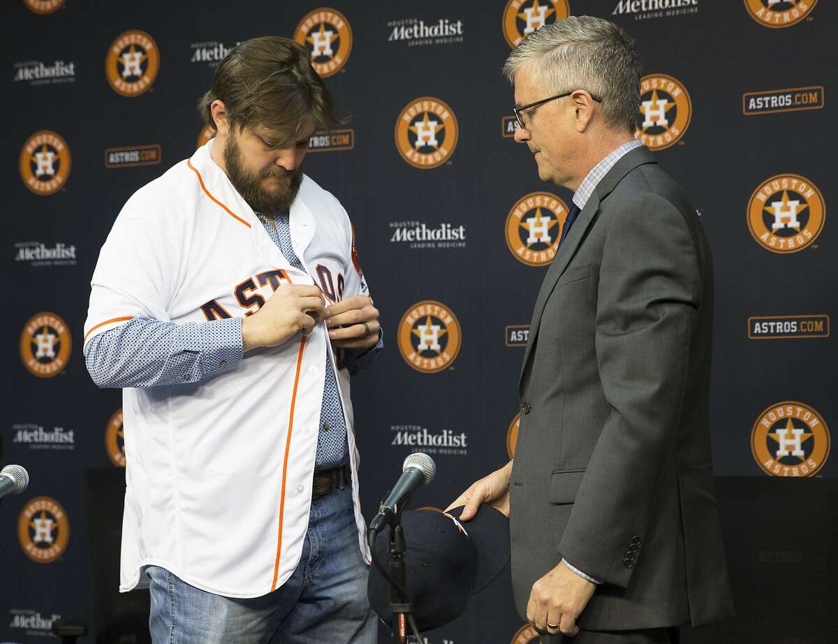 The Houston Astros new pitcher Wade Miley puts on the Astros jersey that he received from general manager Jeff Luhnow during a press conference at Minute Maid Park on Friday, Feb. 1, 2019, in Houston. Miley and the Astros reached a one-year, $4.5 million deal.