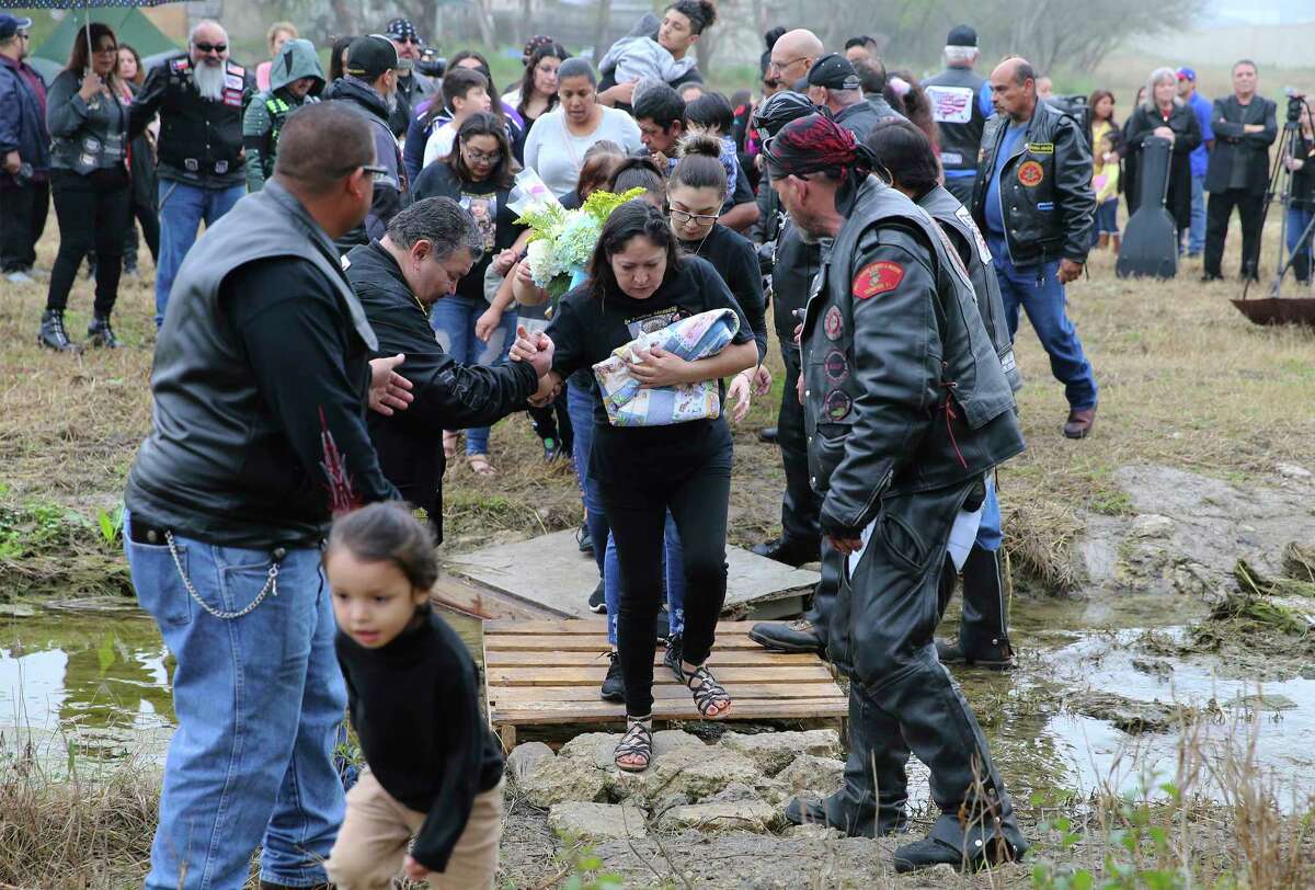The maternal grandmother of baby King Jay Davila gets escorted over a creek during a memorial ceremony near the site of where the 8-month-old was buried by his father. Family, supporters and friends who knew Davila gathered for a memorial service at Christian World Worship Center on Saturday, Feb. 2, 2019. The service was hosted by the child advocacy group Eagles Flight and its executive director Pamela Allen. After the service, a procession went to the site of where the baby's father, Chris Davila, buried the 8-month-old child on the city's Northeast side. At the site, a prayer service was held and doves were released by the child's maternal grandmother. Mourners were given packets of seed to spread in the field. At the conclusion, one of the white doves which were released stayed steadfast at the site as the small crowd slowly left the service.